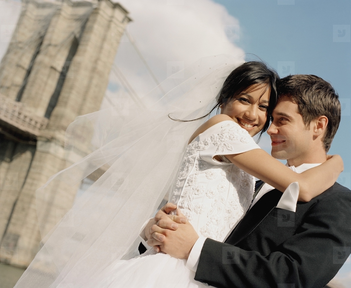 Bride and groom hugging by the Brooklyn Bridge