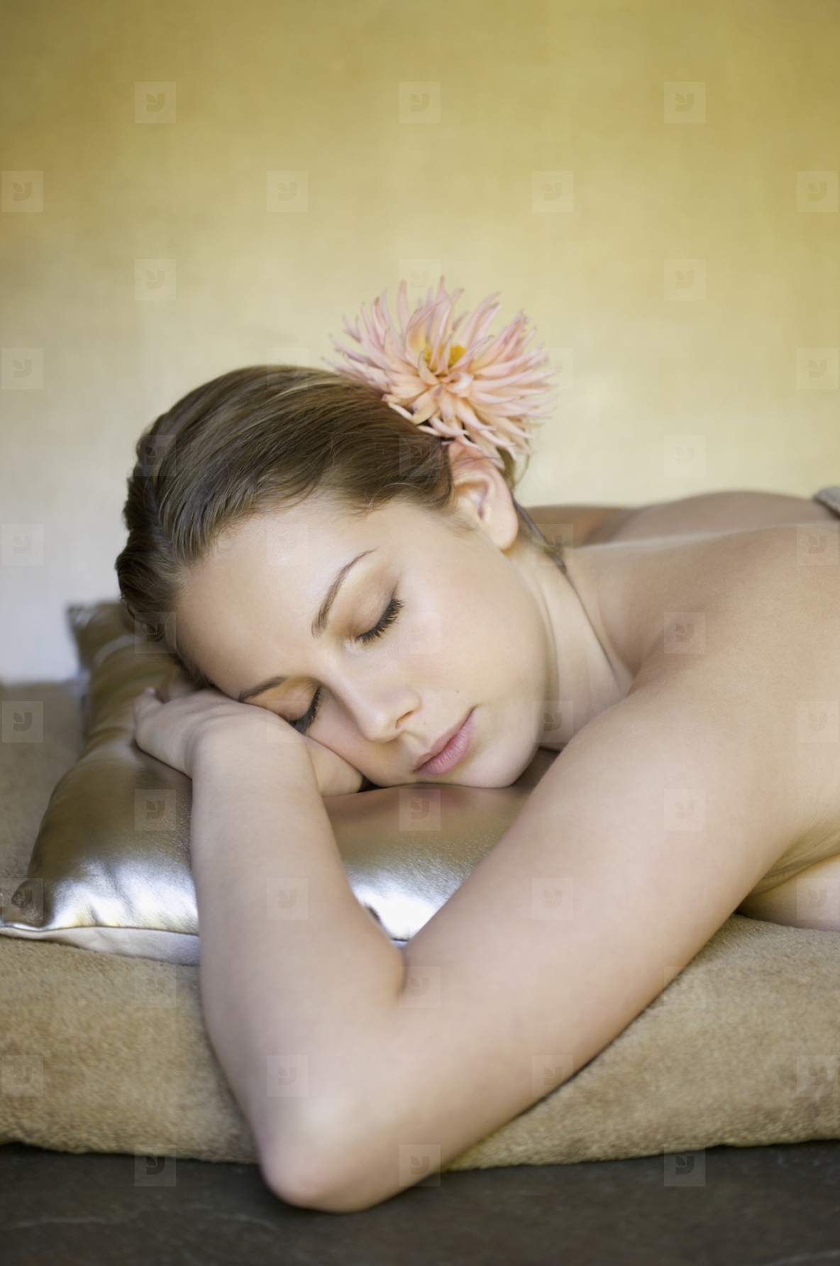 Young woman resting on a gold pillow with her eyes closed