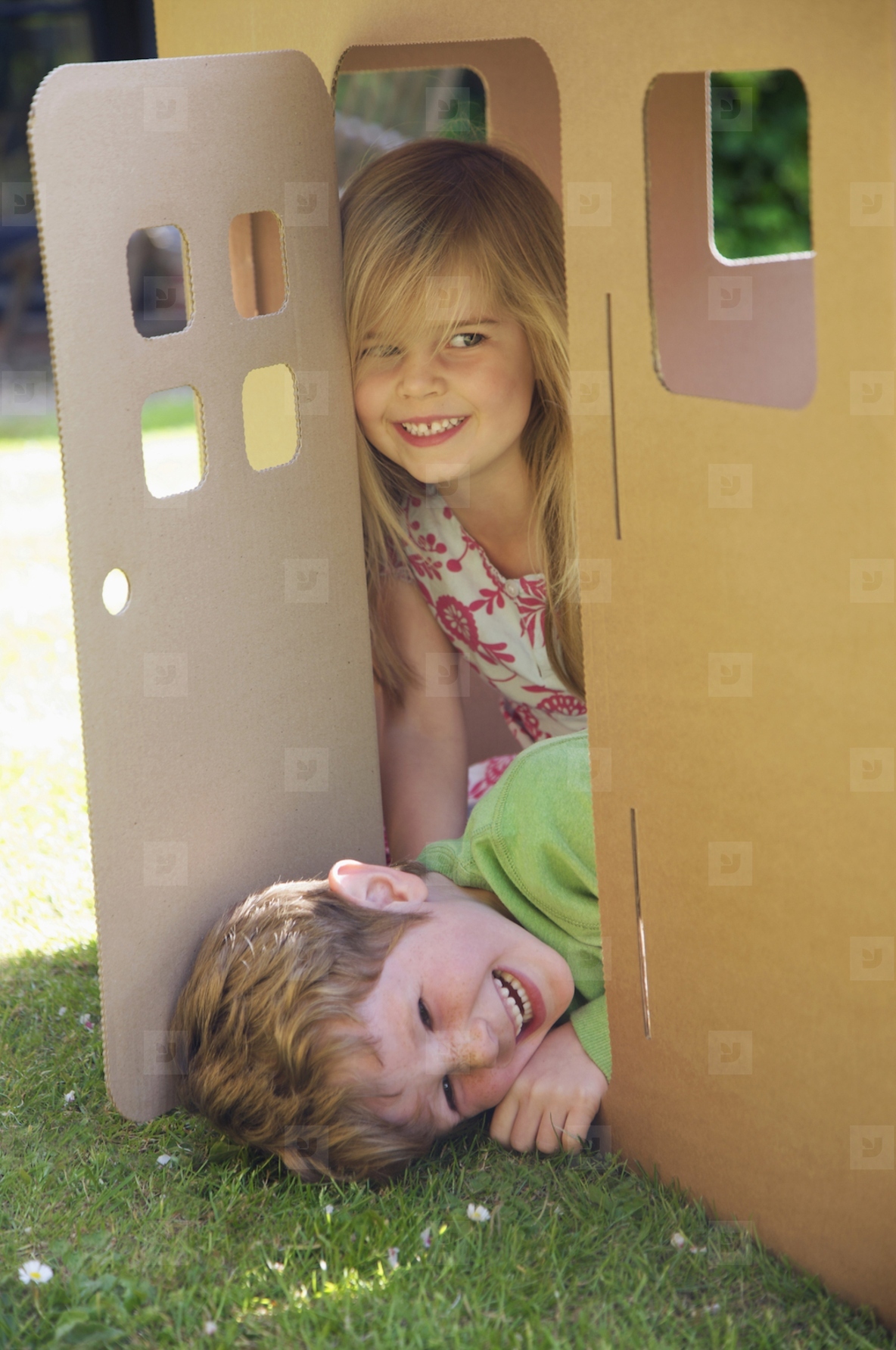 Boy and girl smiling in the doorway of a cardboard playhouse