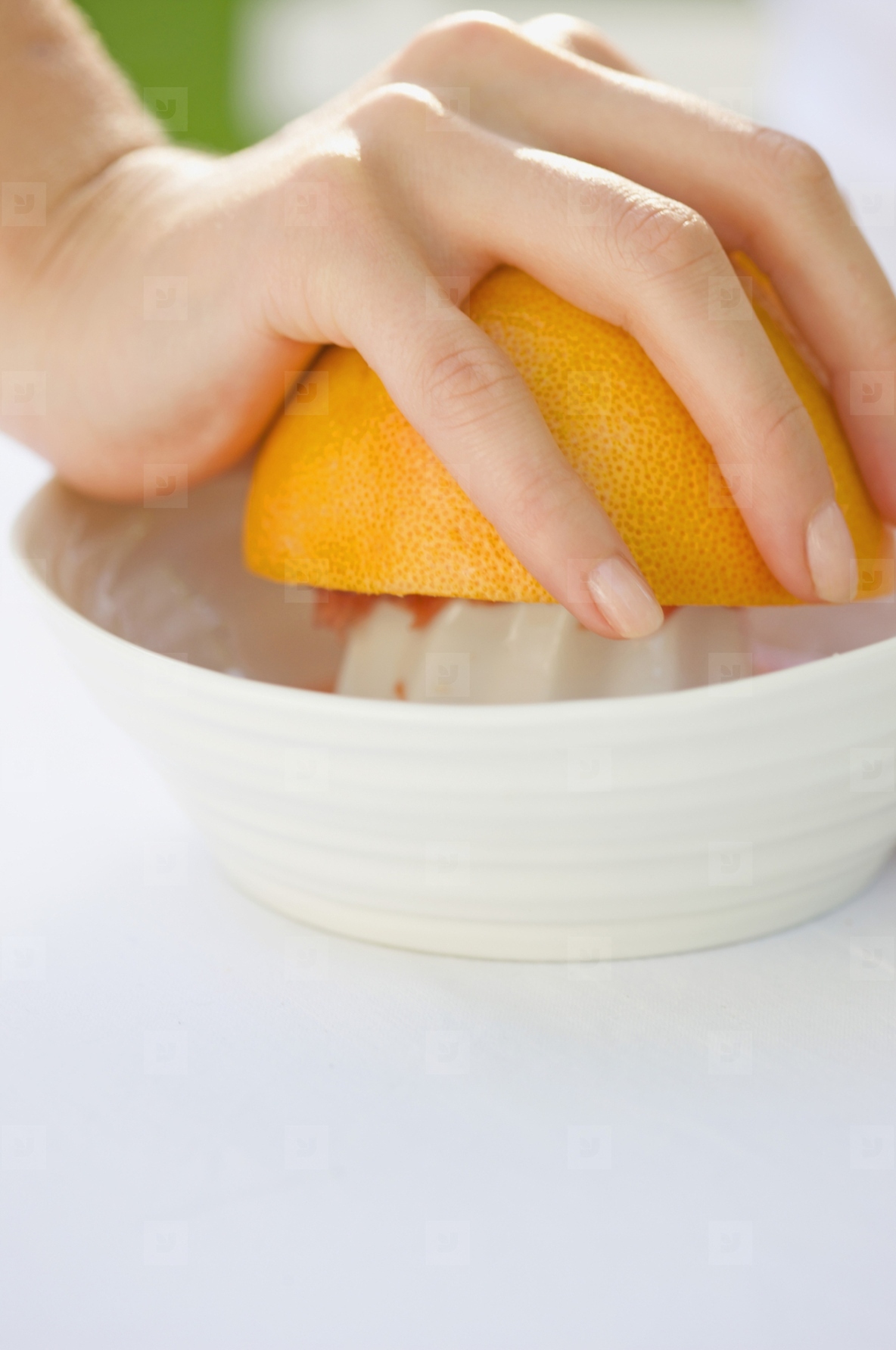 Close up of a womans hand squeezing an orange on a juicer