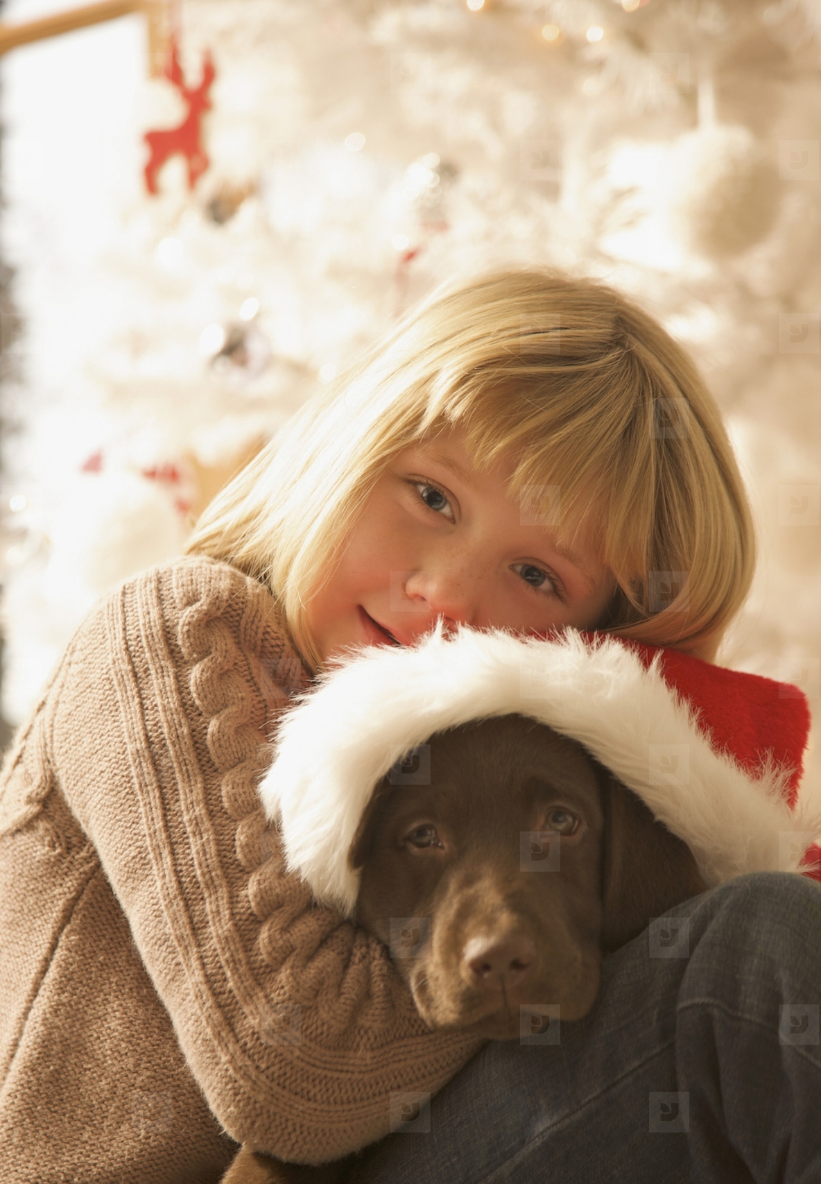 Young girl hugging a puppy wearing a Christmas hat