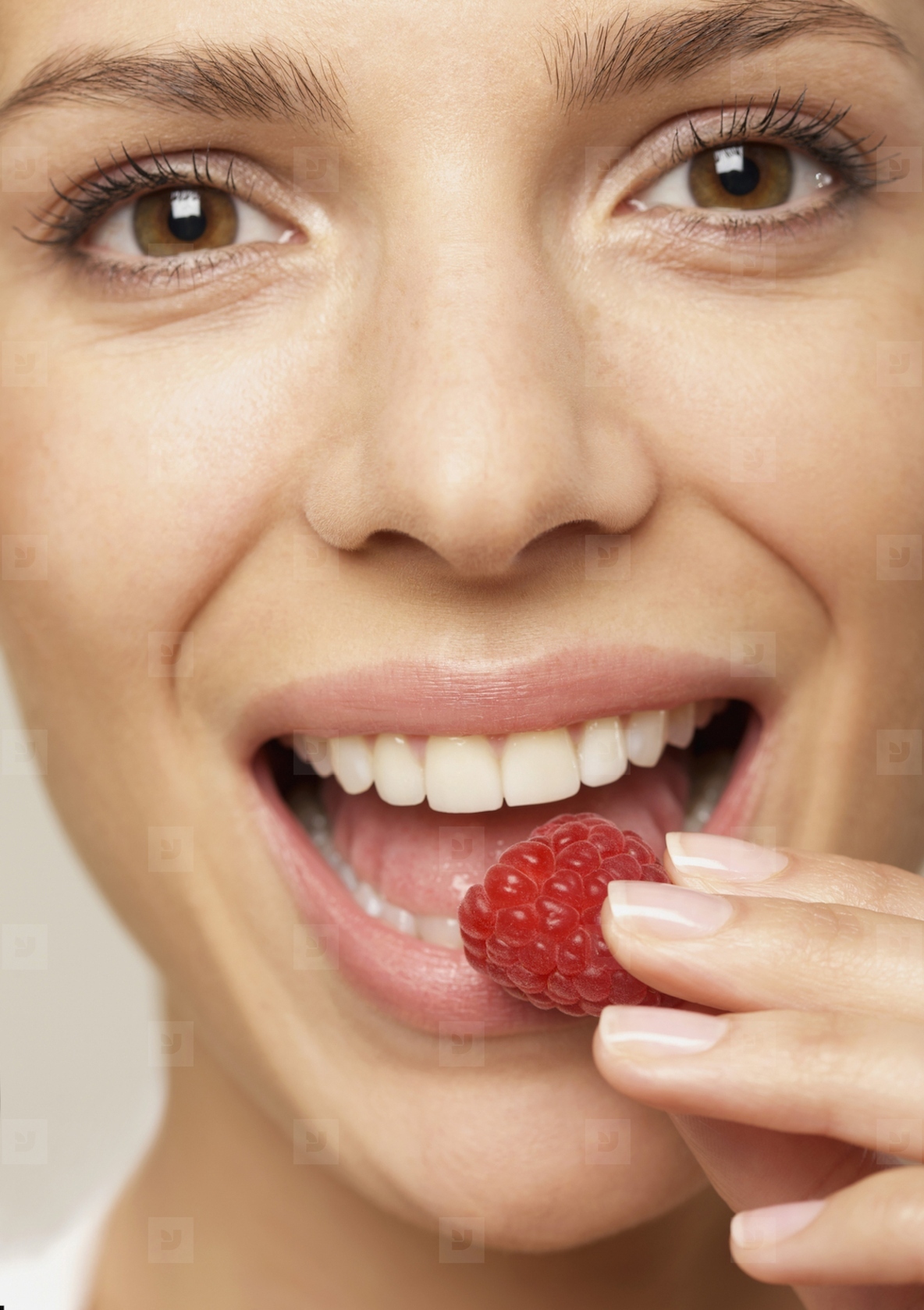 Close up of a young woman eating a raspberry