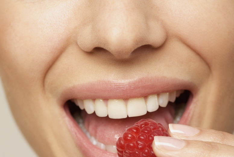 Close up of a young woman eating a raspberry