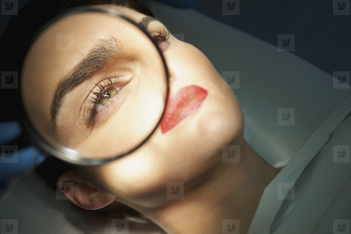 Doctors Hand Holding Magnifying Glass over Womans Eye