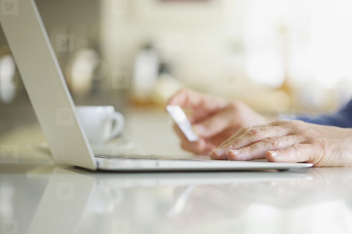 Close up of Mans Hands Holding Credit Card and Using Laptop