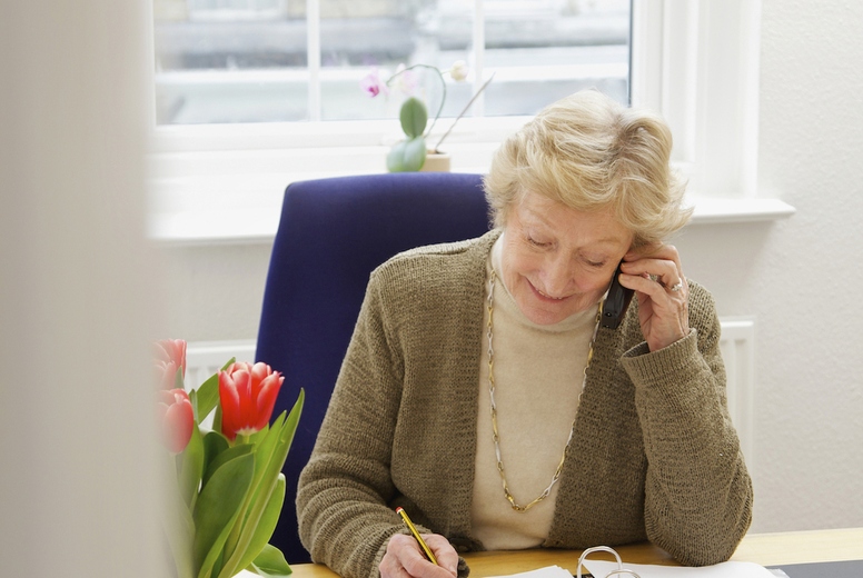 Senior Businesswoman Sitting at Desk Using Telephone