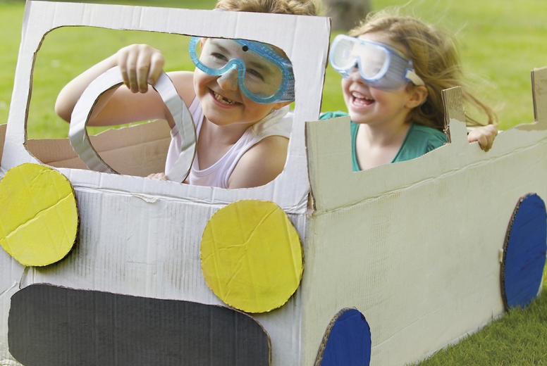 Boy and Girl Wearing Goggles Driving Cardboard Car