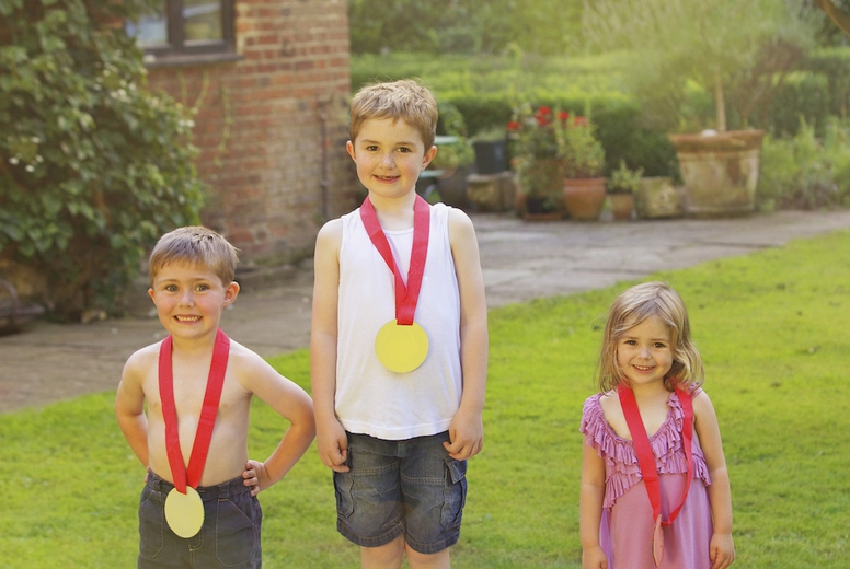 Children Standing on Cardboard Podium with Medals