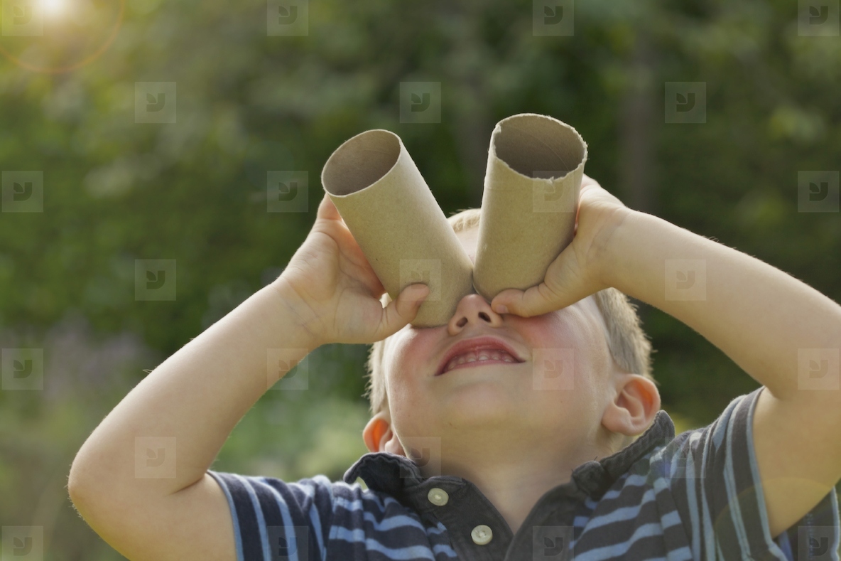 Young Boy Looking Through Empty Toilet Paper Rolls