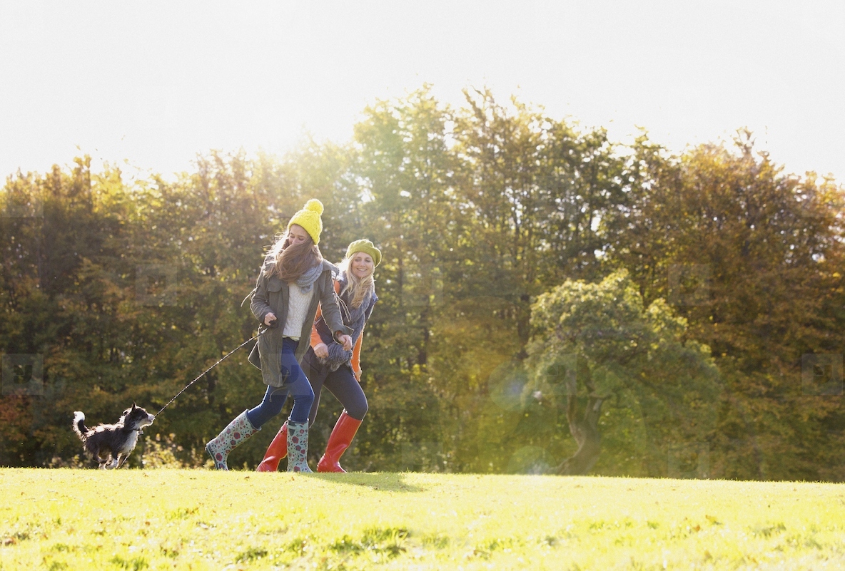 Mother and Daughter Running in Park with Dog