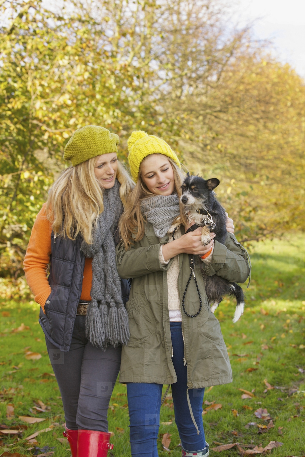Mother and Daughter Walking in Park Carrying Dog