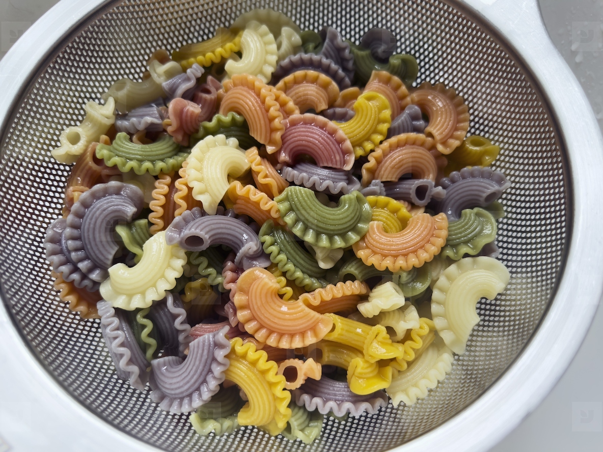 Close up view from above multicolored pasta in colander