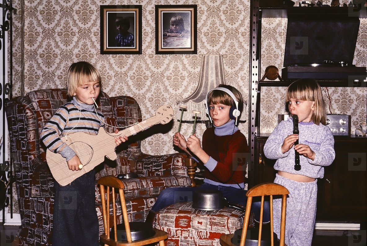 Brothers and sister playing musical instruments in living room
