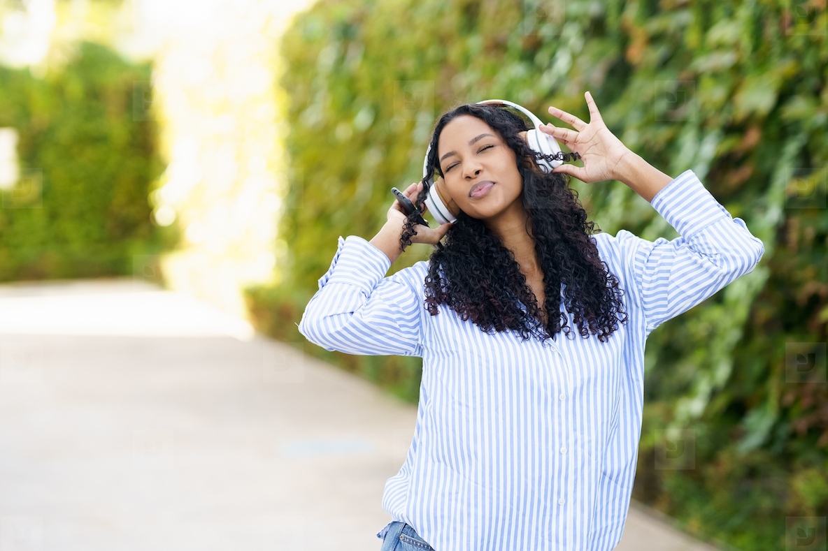 A lively and energetic young woman is thoroughly enjoying her music while outside in nature