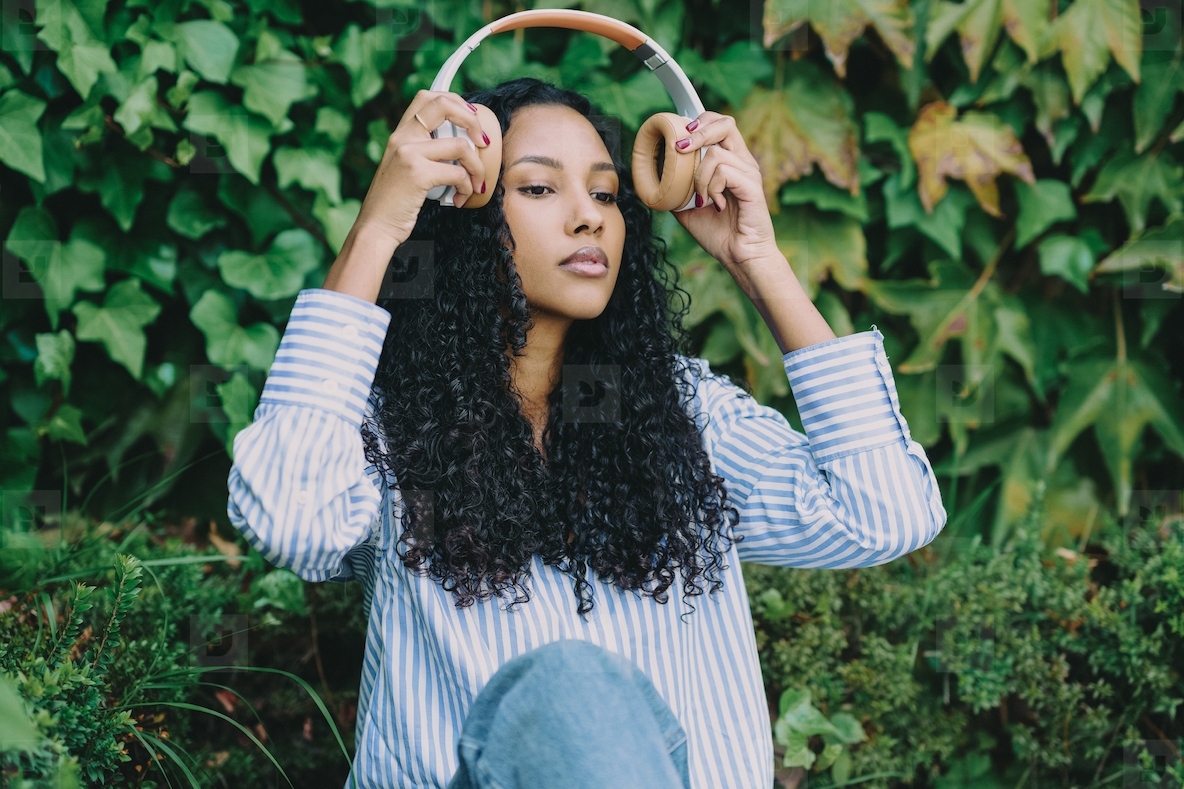 A young woman is thoroughly enjoying some music while relaxing outdoors with her headphones on