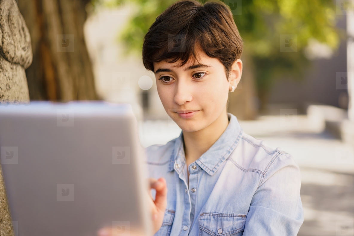 A Young girl Engaged in Using a Tablet While Enjoying an Outdoor Setting in Daylight