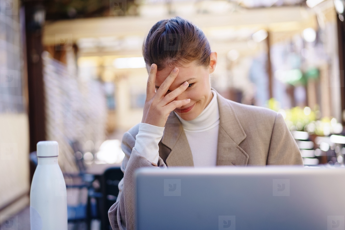 A frustrated professional is trying to work on a laptop outside  facing many distractions