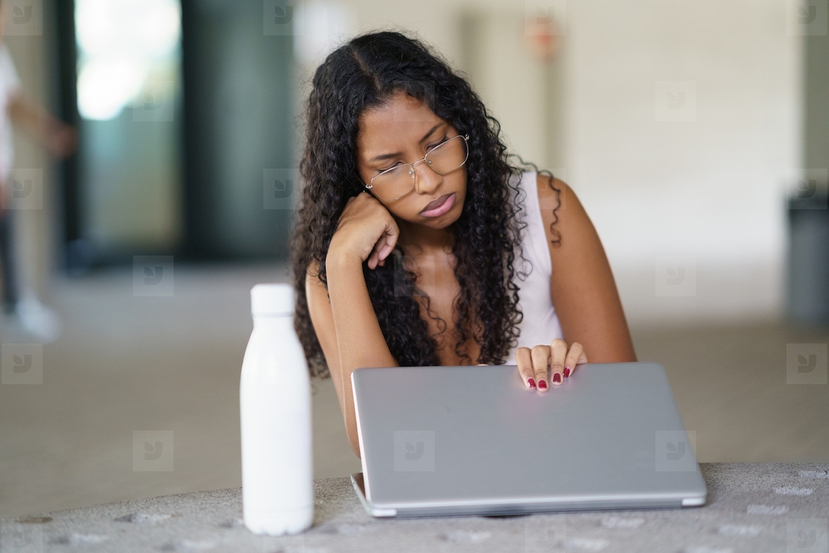 A Highly Focused Woman Diligently Engaged in Her Work on a Laptop Inside a Casual Indoor Setting