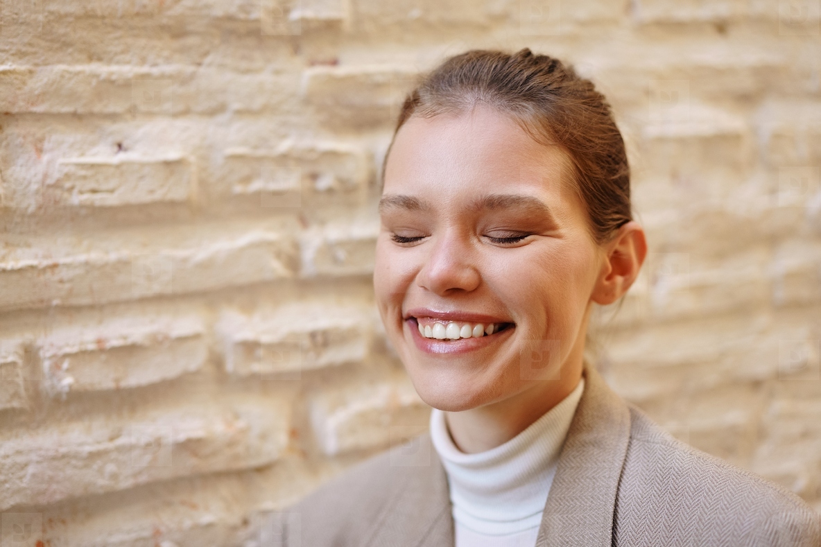 A Woman Smiling Joyfully Against a Textured Wall  Radiating Warmth and Happiness