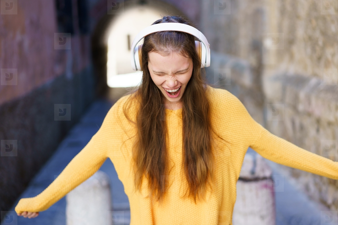 A Joyful Young Woman is Delightedly Enjoying Music While Wearing a Bright Yellow Sweater