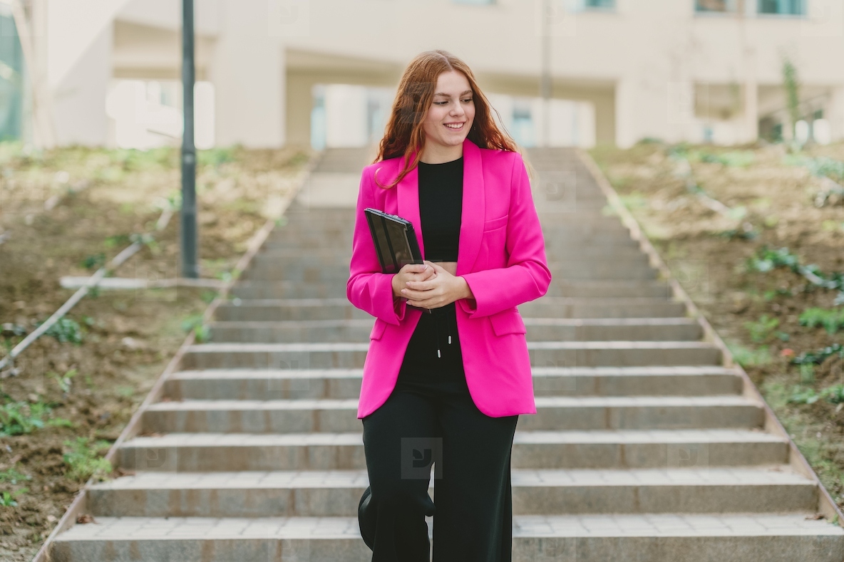 A Confident Businesswoman Wearing a Vibrant Pink Blazer Poses on the Steps Outside