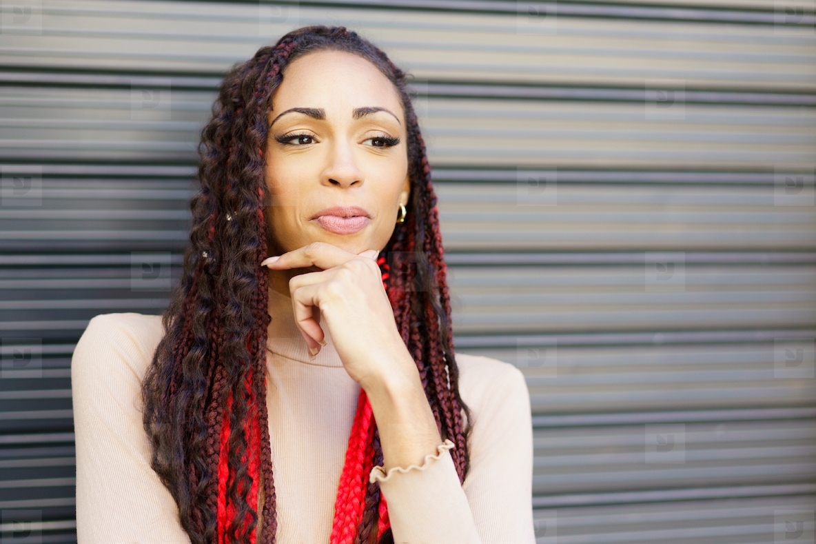 A thoughtful and contemplative woman with intricately braided hair in an urban setting