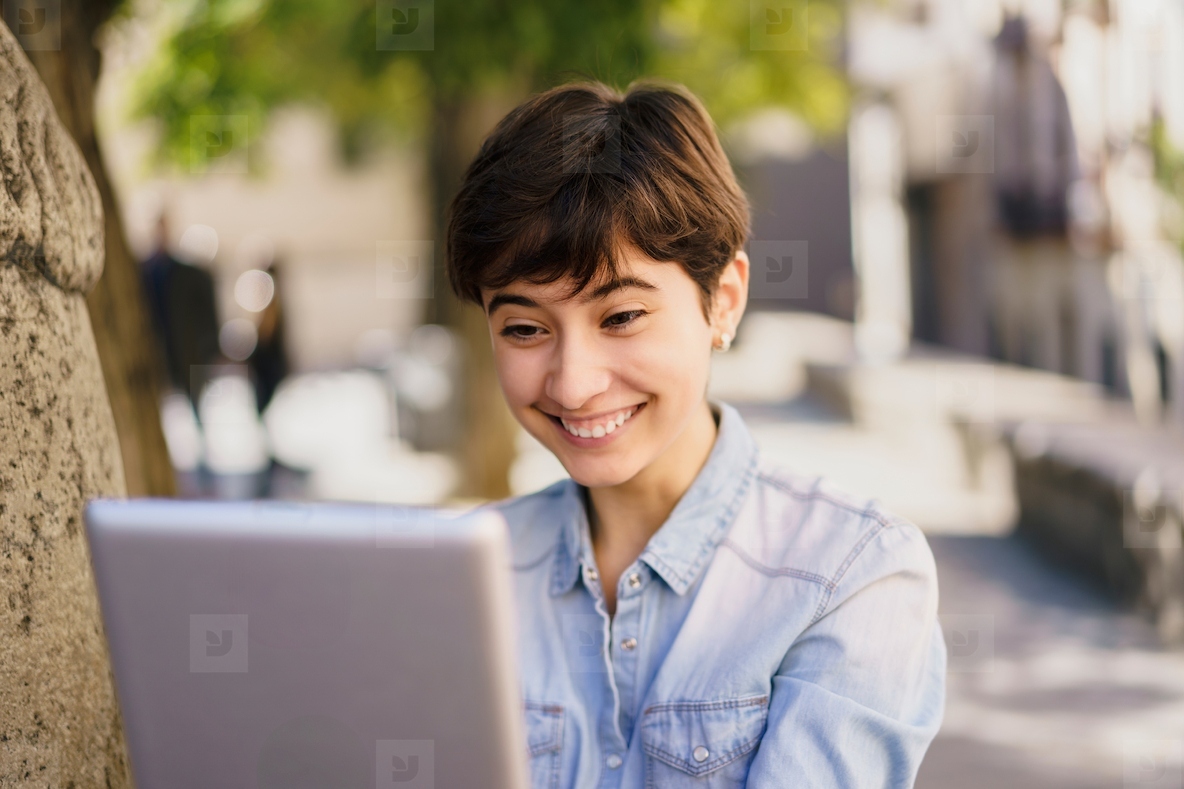 A Joyful Young Woman Enthusiastically Using Her Laptop Outdoors Surrounded by Nature