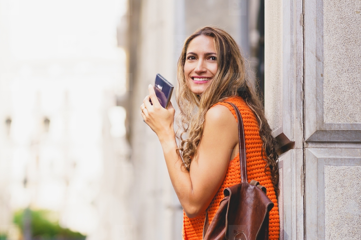 Woman smiling while holding mobile phone in the city