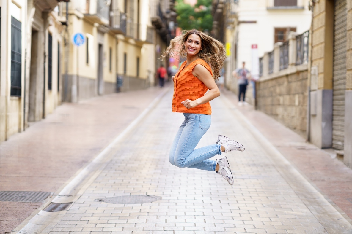 Latin woman jumping in the middle of street