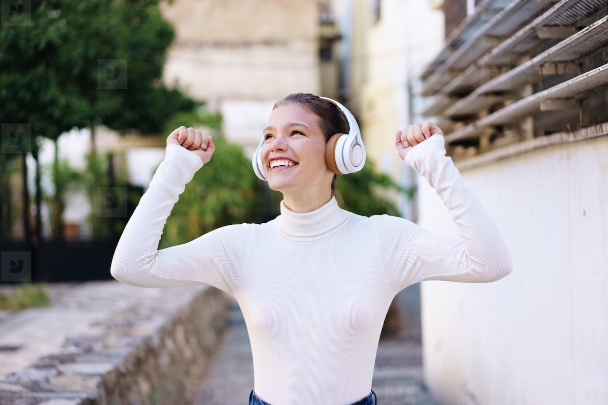 A Joyful and Carefree Young Woman Joyfully Enjoying Music While Outdoors in Daylight