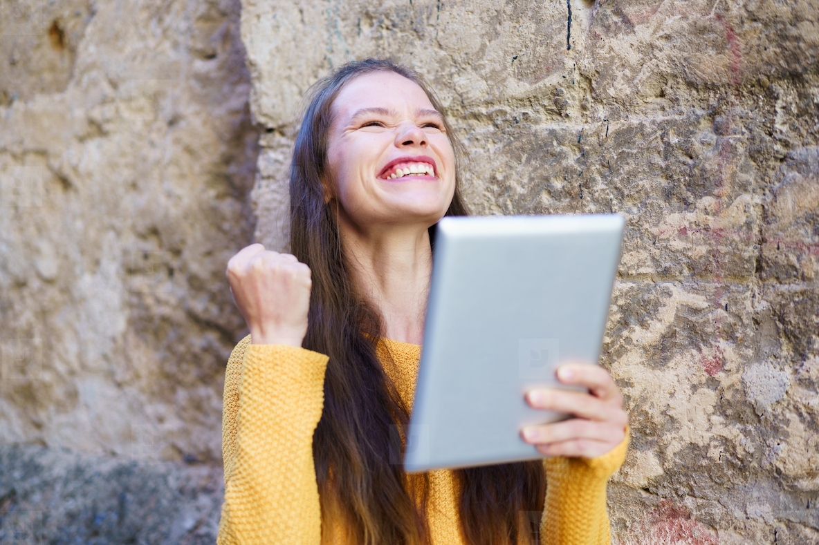 A Joyful Young Woman is Celebrating with a Tablet in Her Hand  Radiating Happiness and Enthusiasm