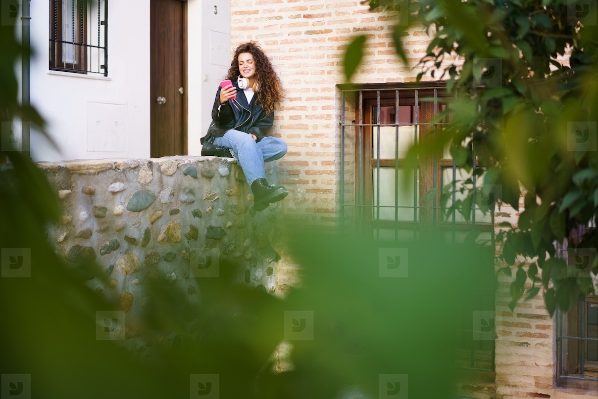 A Young Woman Delightfully Enjoying a Refreshing Drink Outdoors in an Urban Setting
