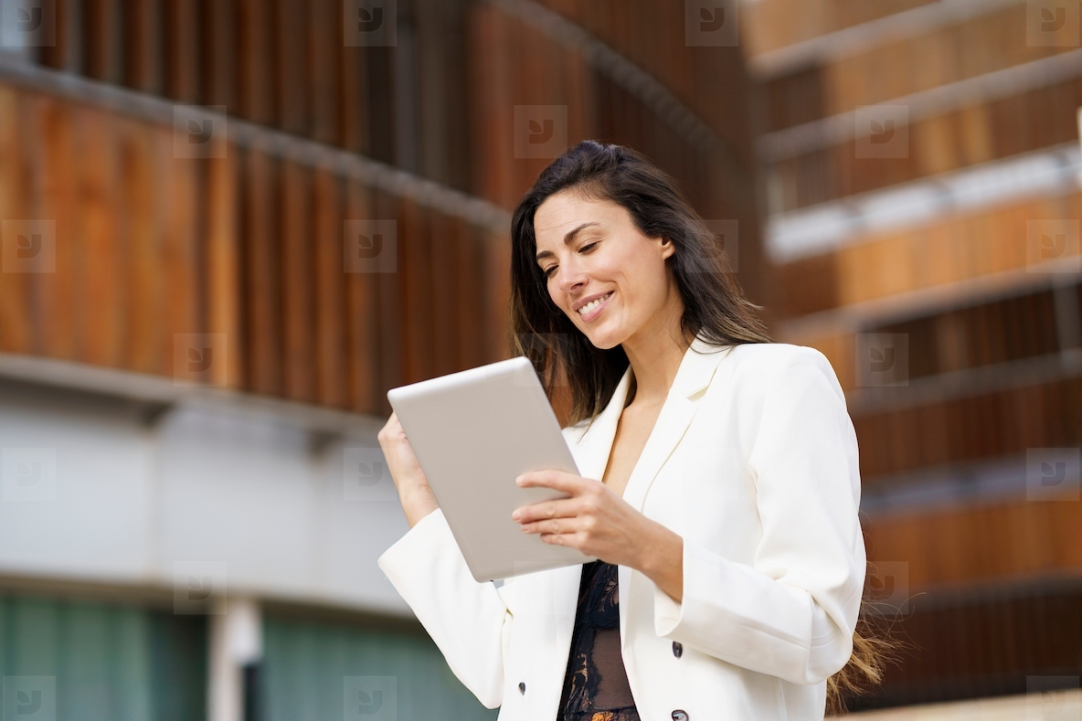 A young woman is using a tablet in a vibrant and modern urban setting within the city