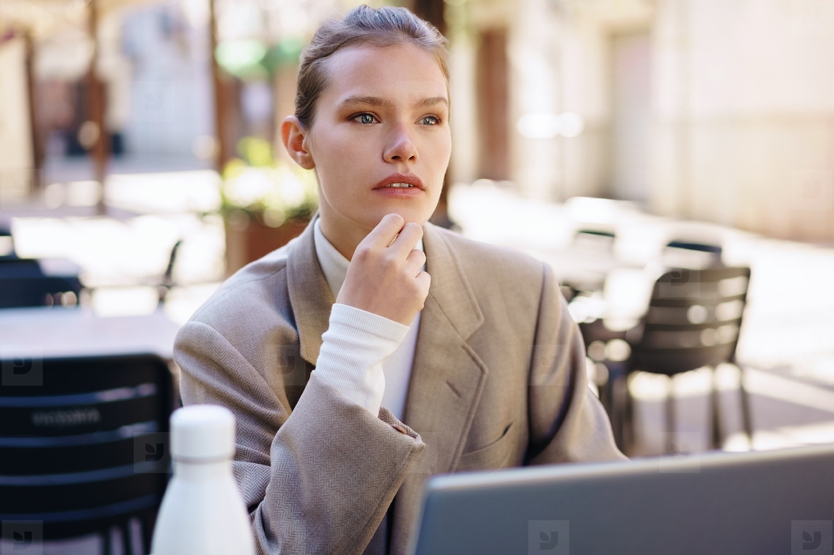 A thoughtful professional woman diligently working outdoors on her laptop  immersed in her tasks