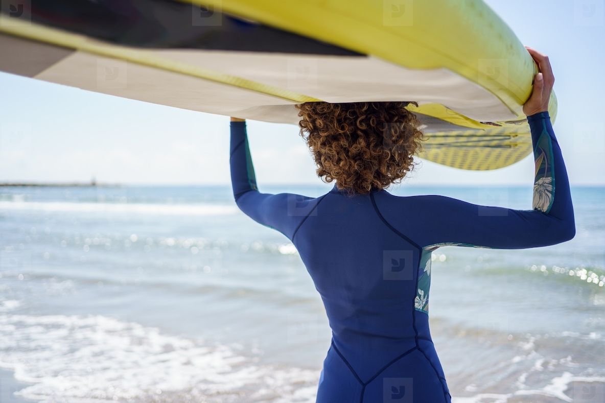 Young woman with SUP board in swimsuit on beach