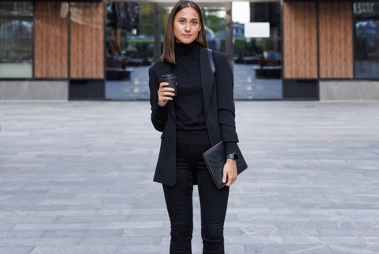 Full length of young female entrepreneur holding a digital tablet and coffee in front of an office building