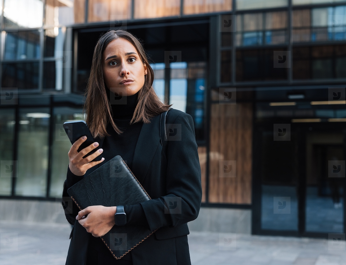 Young businesswoman in black formal attire Confident female with smartphone looking at camera