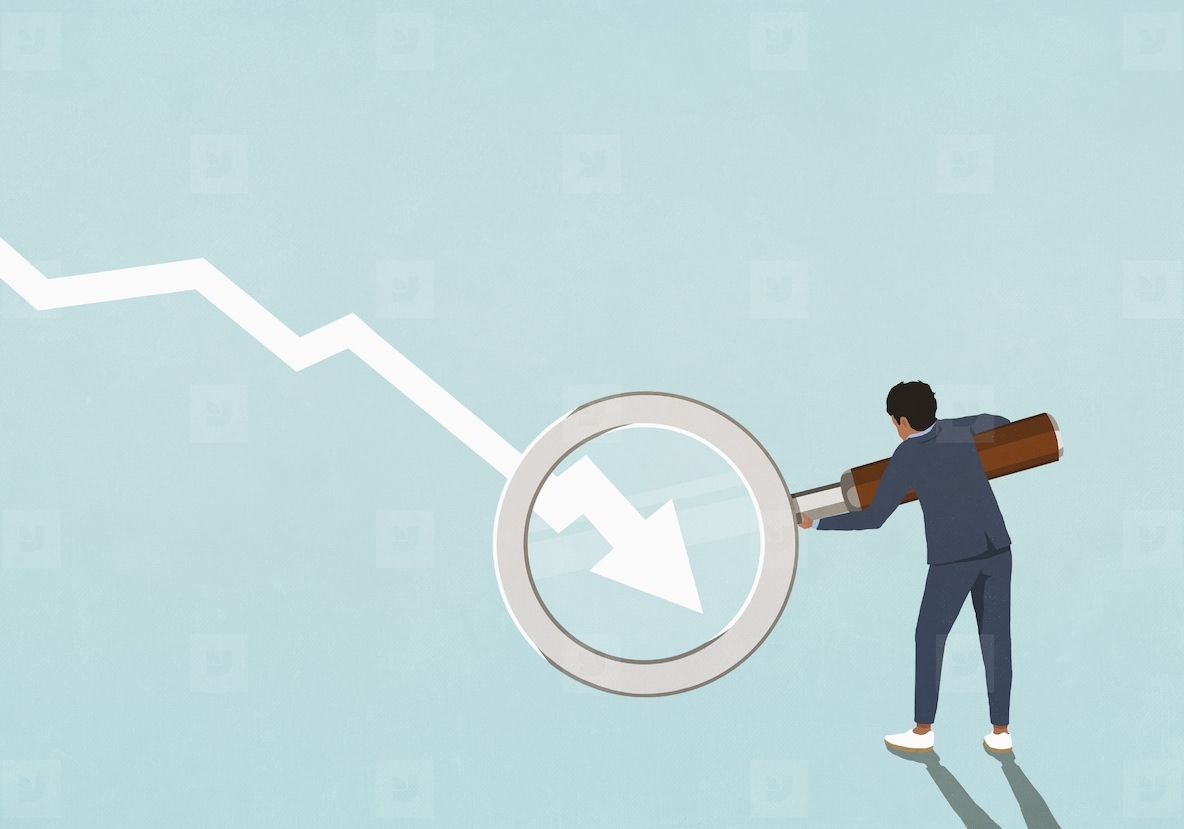 Businessman holding magnifying glass over descending chart arrow