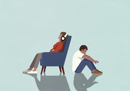 Man sitting on floor behind woman listening to music with headphones and relaxing in armchair
