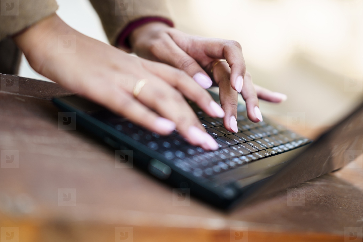 Elegant Hands Gracefully Typing on a Modern Laptop Keyboard in a Focused Workspace Setting