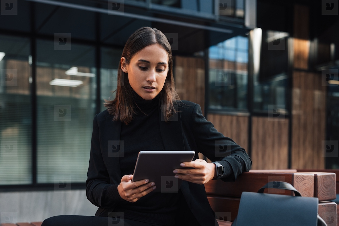 Beautiful brunette businesswoman holding a digital tablet Young female reading from digital tablet outside