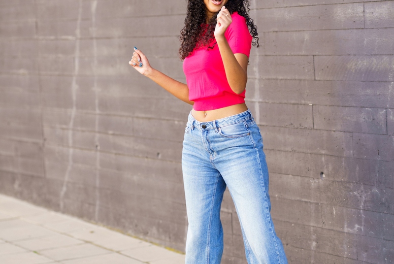 A Joyful Woman is Dancing Enthusiastically in an Urban Setting, Showcasing a Trendy Outfit