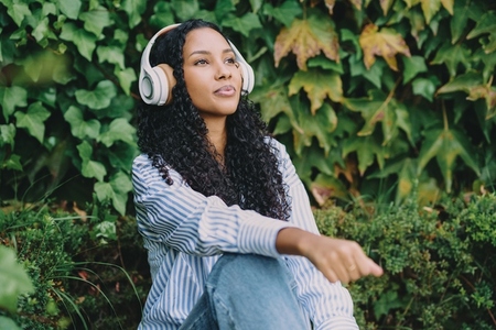 A Relaxed Young Woman Enjoying Listening to Music in a Beautiful Natural Setting Outdoors