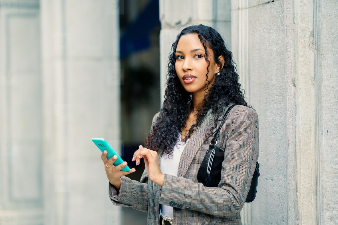 A Stylish Young Woman Engaged in Using Her Smartphone While in an Urban Setting Outdoors