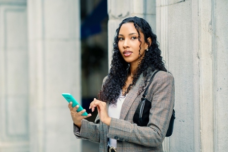 A Stylish Young Woman Engaged in Using Her Smartphone While in an Urban Setting Outdoors