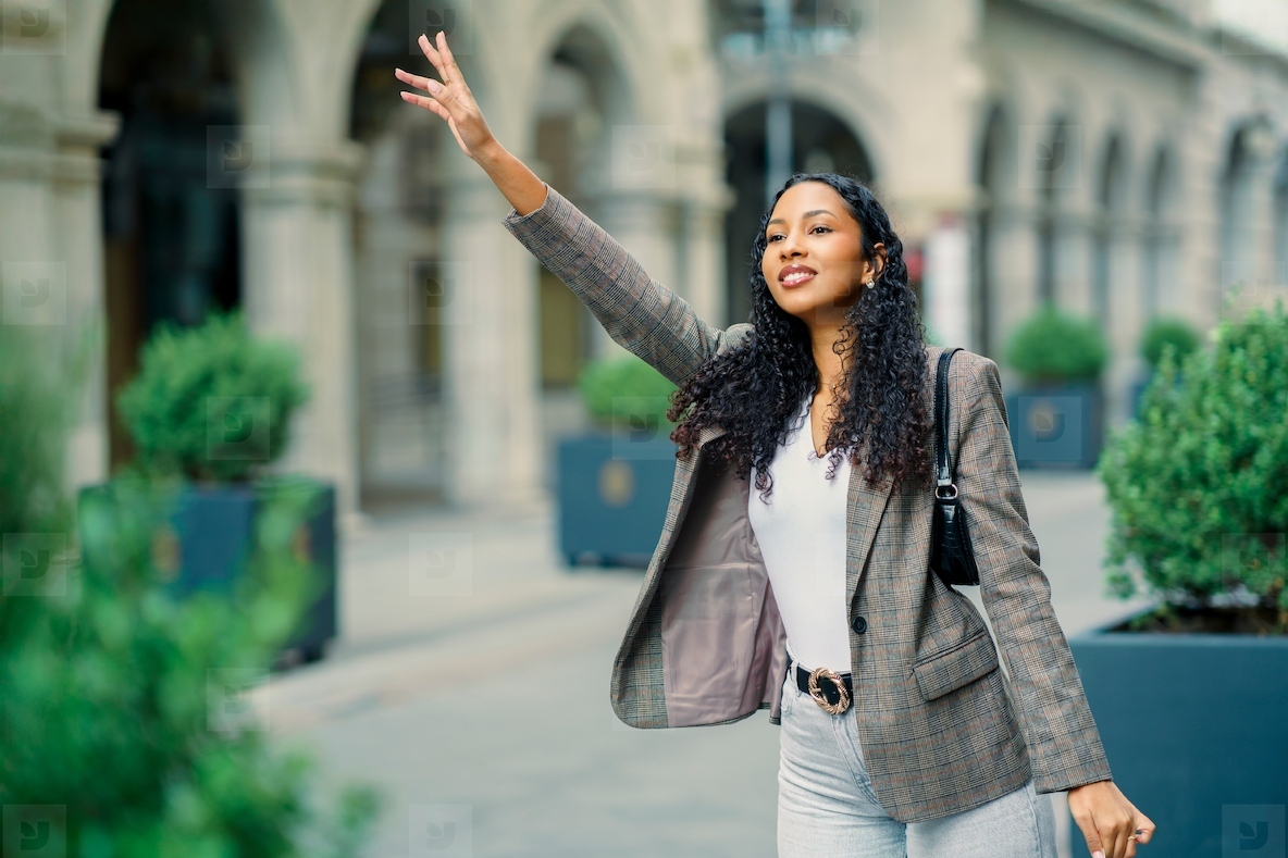 A charming young woman is cheerfully waving in a vibrant urban setting filled with life