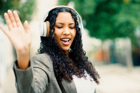 A Joyful Young Woman is Delightfully Enjoying Music Outdoors while Wearing Headphones