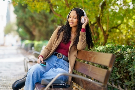 A Young Woman Sitting on a Bench  Enjoying Music in a Peaceful Park Setting  Relaxing