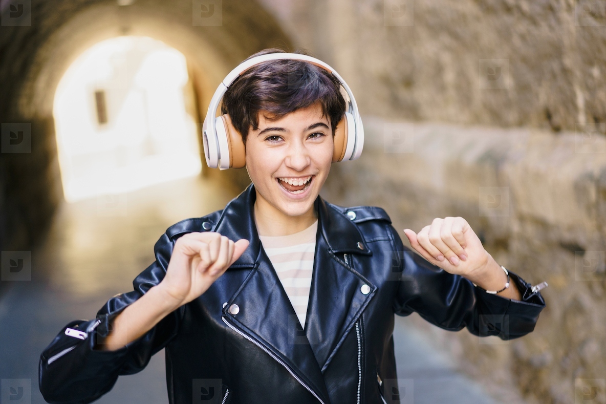 Joyful and energetic youth are dancing wearing headphones in a lively urban environment
