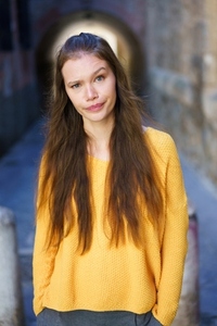 A Young Woman Dressed in a Vibrant Yellow Sweater Posing Confidently in a Trendy Urban Alley